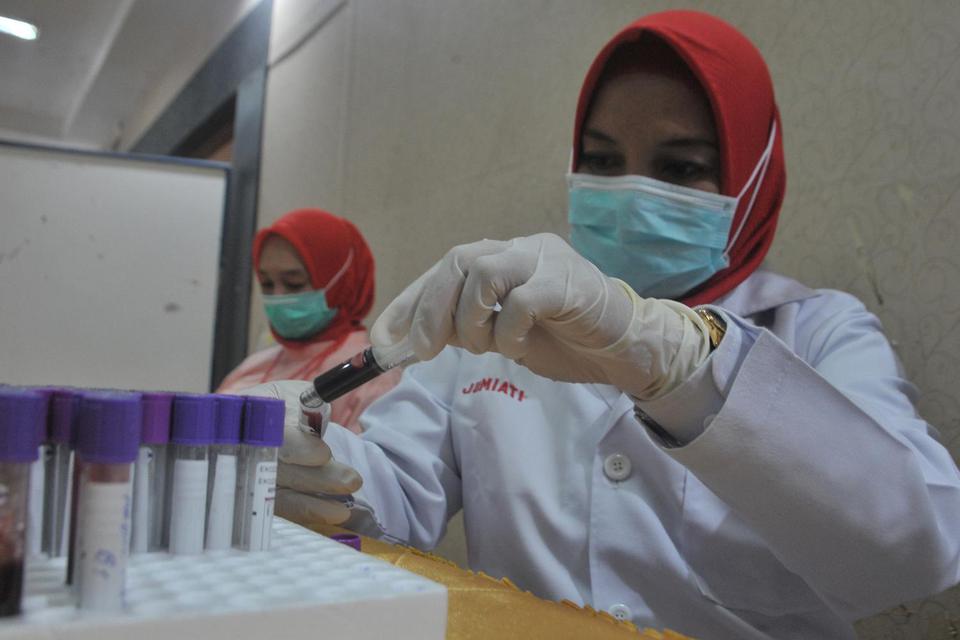 Petugas Palang Merah Indonesia (PMI) memindahkan sampel darah penyintas Covid 19 yang akan menjadi pendonor plasma konvalesen pada gelar donor darah di komplek Pertamina RU III Palembang, Sumatera Selatan, Selasa (23/2/2021). 