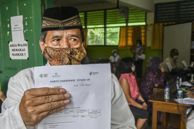 Warga lansia (lanjut usia) menunjukkan kartu vaksinasi di SD 05, Penggilingan, Jakarta Timur, Kamis (25/2/2021). Pemerintah menargetkan 21,5 juta lansia akan mendapat vaksin COVID-19 guna mengurangi penyebaran wabah COVID-19.
