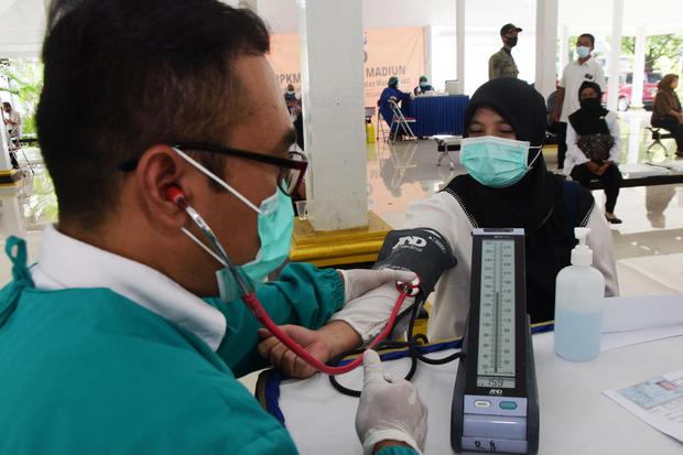 Petugas medis mememeriksa kondisi kesehatan seorang tenaga pendidik sebelum penyuntikkan vaksin COVID-19 di Posko Pemberlakukan Pembatasan Kegiatan Masyarakat (PPKM) Mikro di Kabupaten Madiun, Jawa Timur, Rabu (3/3/2021). Pemkab Madiun memfasilitasi vaksi