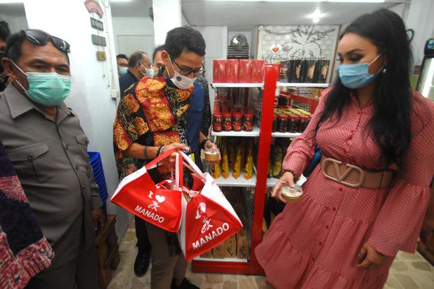 Menteri Pariwisata dan Ekonomi Kreatif Sandiaga Uno (tengah) berbelanja cinderamata di salah satu pusat oleh-oleh, Manado, Sulawesi Utara, Jumat (5/3/2021). Kunjungan tersebut untuk meninjau potensi pengembangan Usaha Kecil Mikro Menengah (UMKM) untuk men