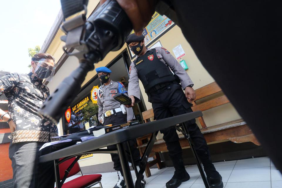 Petugas memeriksa pengunjung menggunakan metal detector di Polres Kediri Kota, Kota Kediri, Jawa Timur, Rabu (31/3/2021). Polisi memperketat penjagaan di tempat tersebut dengan memeriksa barang bawaan pengunjung sekaligus melarang parkir kendaraan di hala