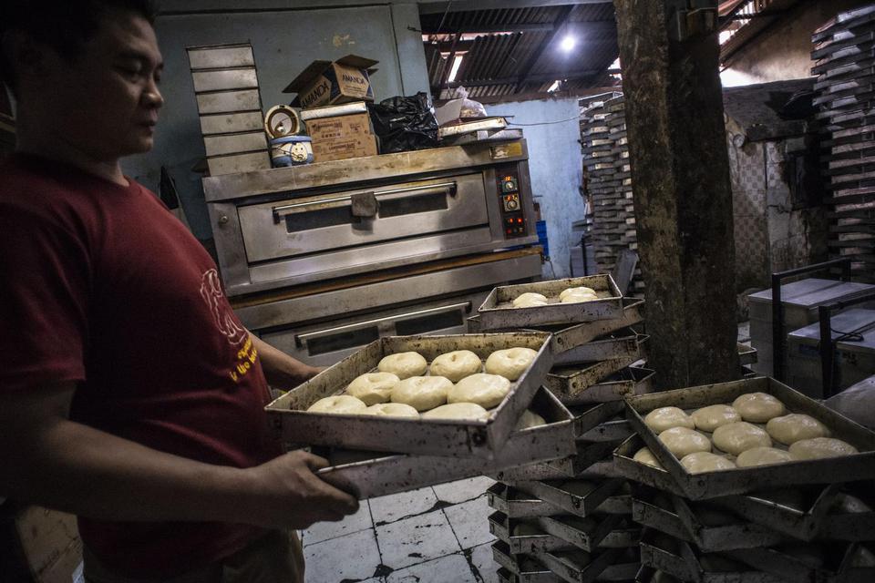 Pekerja memindahkan loyang berisi adonan roti di salah satu industri rumahan kawasan Bendungan Hilir, Jakarta, Selasa (20/4/2021). Pemerintah akan memberikan stimulus kredit usaha mikro kecil menengah (UMKM) sebesar Rp400 miliar dalam rangka mendorong per