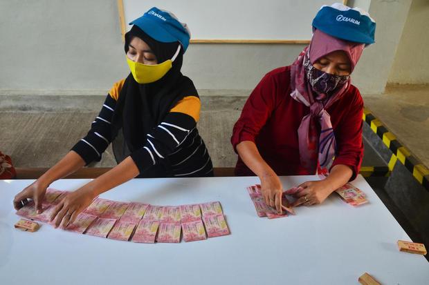Pekerja menghitung uang Tunjangan Hari Raya (THR) yang diterimanya di pabrik rokok PT Djarum, Kudus, Jawa Tengah, Kamis (29/4/2021).