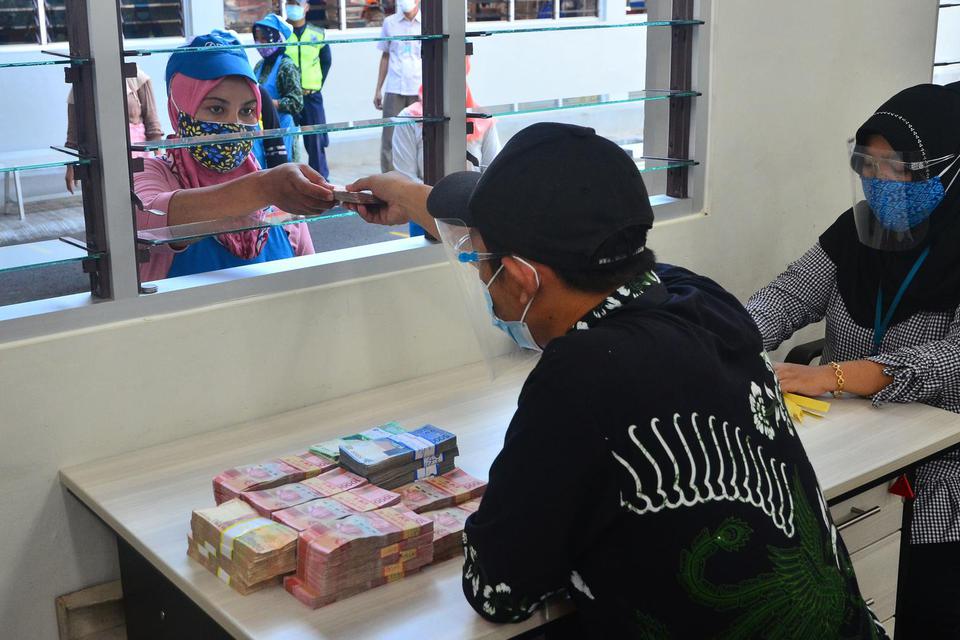 Pekerja menerima uang Tunjangan Hari Raya (THR) yang diterimanya di pabrik rokok PT Djarum, Kudus, Jawa Tengah, Kamis (29/4/2021). Sebanyak 51.451 pekerja harian dan borongan di perusahaan itu menerima uang THR guna membantu mereka dalam memenuhi kebutuh