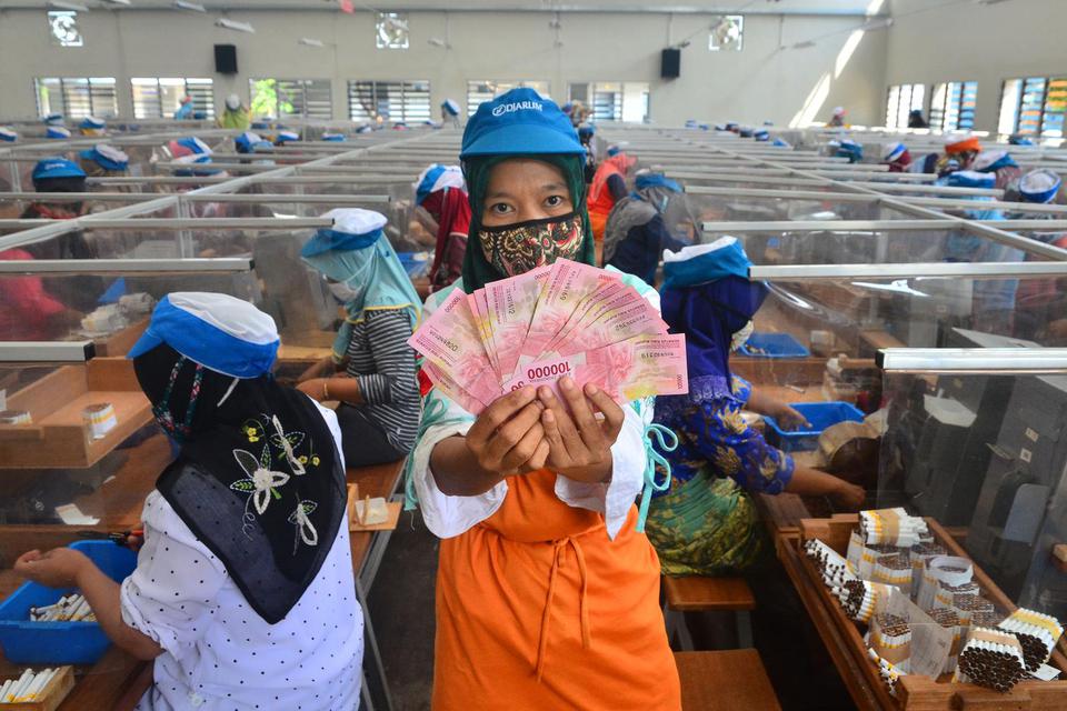 Pekerja menunjukkan uang Tunjangan Hari Raya (THR) yang diterimanya di pabrik rokok PT Djarum, Kudus, Jawa Tengah, Kamis (29/4/2021). Sebanyak 51.451 pekerja harian dan borongan di perusahaan itu menerima uang THR guna membantu mereka dalam memenuhi kebu