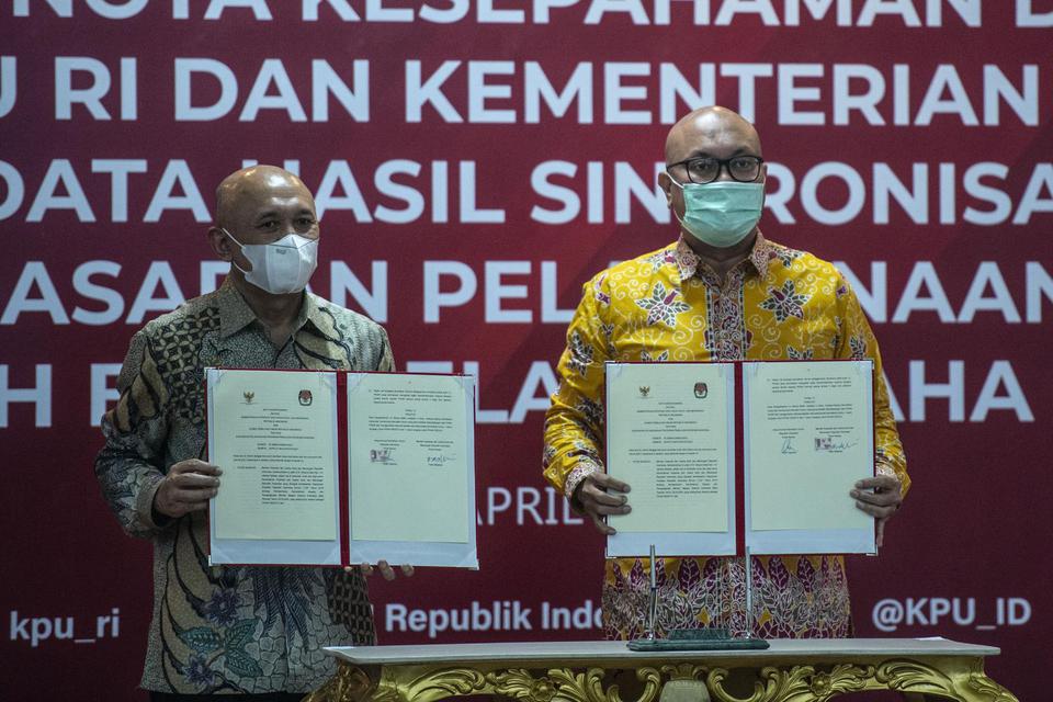Ketua KPU Ilham Saputra (kanan) bersama Menteri Koperasi dan UKM Teten Masduki menunjukan dokumen nota kesepahaman tentang dukungan Pemulihan Ekonomi Nasional (PEN) usai penandatanganan di Kantor KPU, Jakarta, Kamis (29/4/2021). Koperasi adalah sebuah usa