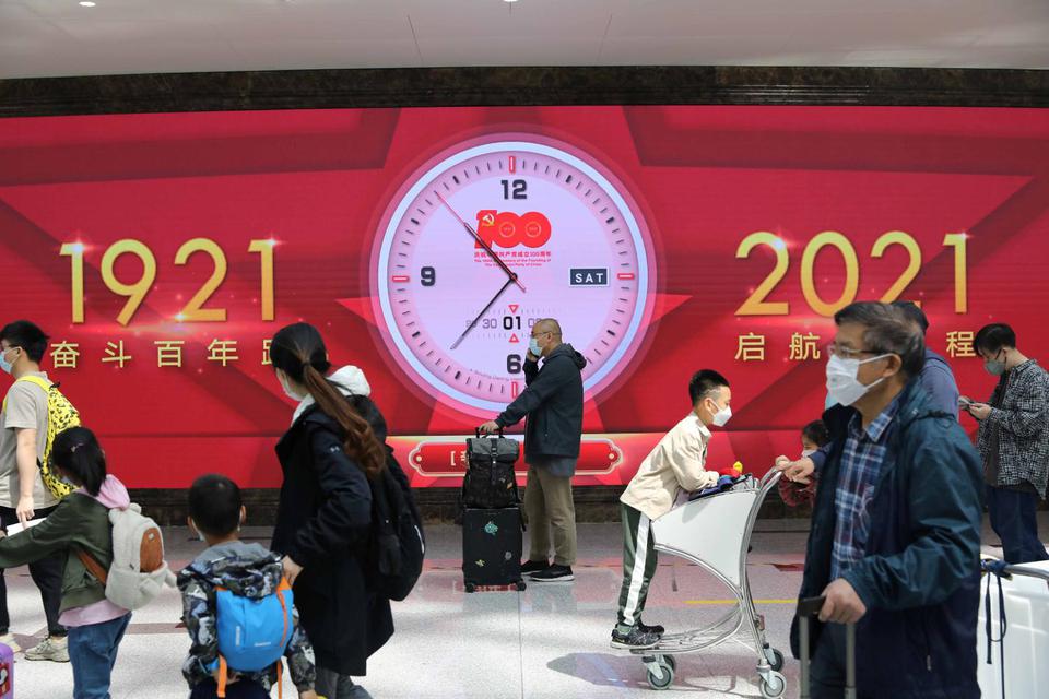 Tingshu Wang Para turis berjalan melewati jam layar raksasa yang memperingati 100 tahun pendirian Partai Komunis China, di Bandara Internasional Daxing Beijing pada hari libur pertama Hari Buruh, di Beijing, China, Sabtu (1/5/2021).