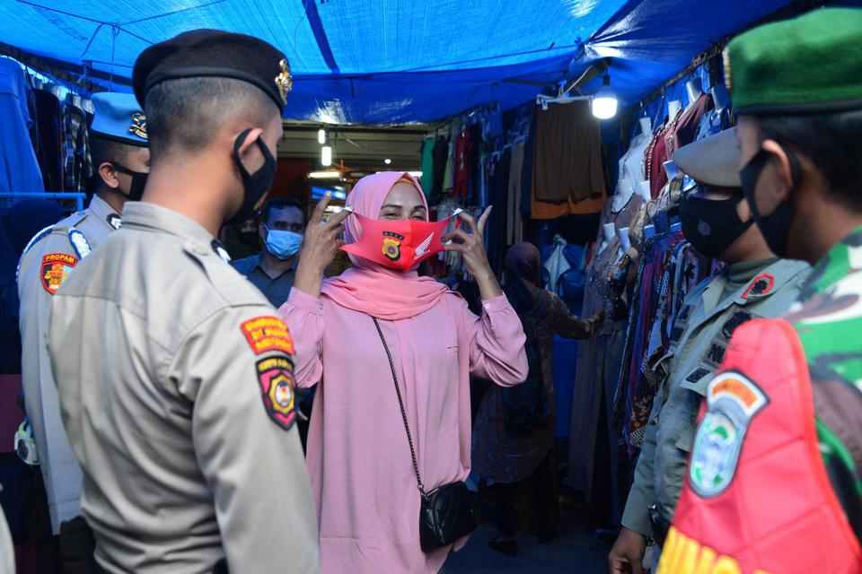 Personil gabungan Polri, TNI dan Satpol PP memberikan masker gratis kepada seorang pedagang saat melakukan pengawasan pusat keramaian di Pasar Aceh, Banda Aceh, Aceh, Kamis (6/5/2021). Polda Aceh mengintensifkan pengawasan menjelang Idul Fitri di sejumlah