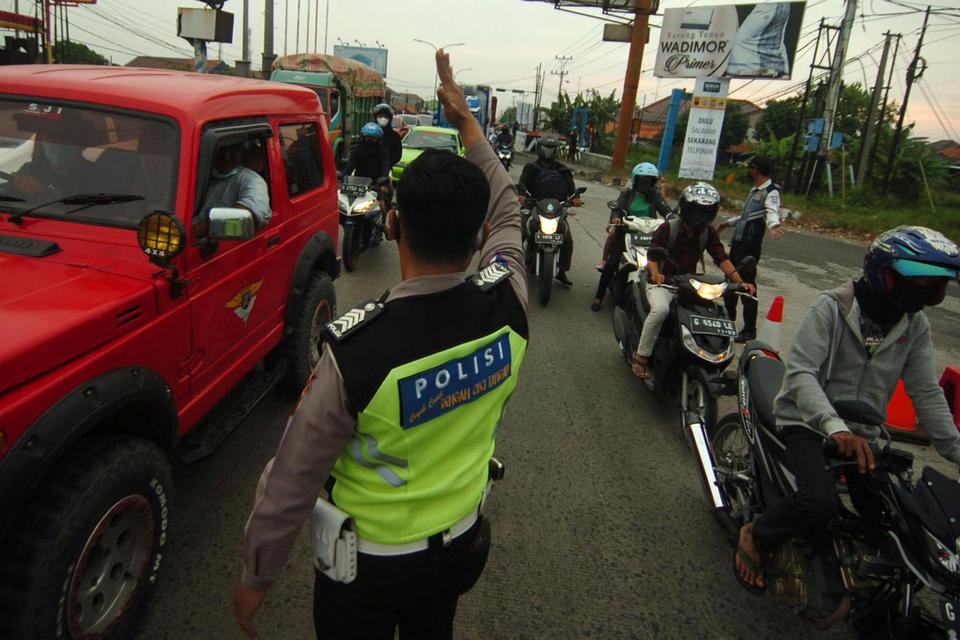 Personel kepolisian mengatur arus lalu lintas di pos penyekatan jalur Pantura, Tegal, Jawa Tengah, Jumat (7/5/2021). Pada hari kedua pemberlakukan penyekatan pemudik, jakur Pantura terpantau ramai lancar didominasi truk dan kendaraan roda dua masyarakat s
