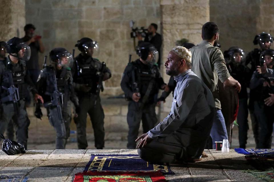 Ammar Awad Seorang pria Palestina berdoa ketika polisi Israel berkumpul selama bentrokan di kompleks yang menampung Masjid Al-Aq yang dikenal oleh muslim sebagai Suaka Mulia dan kepada orang Yahudi sebagai Temple Mount, di tengah ketegangan atas kemungki