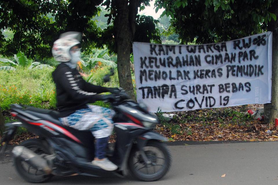 Pengendara motor melintas di dekat spanduk penolakan warga terhadap pemudik di Kelurahan Cimahpar, Kota Bogor, Jawa Barat, Selasa (18/5/2021). Spanduk yang dibuat warga RW 16, Kelurahan Cimahpar, Kota Bogor tersebut untuk memperingatkan para pemudik yang 