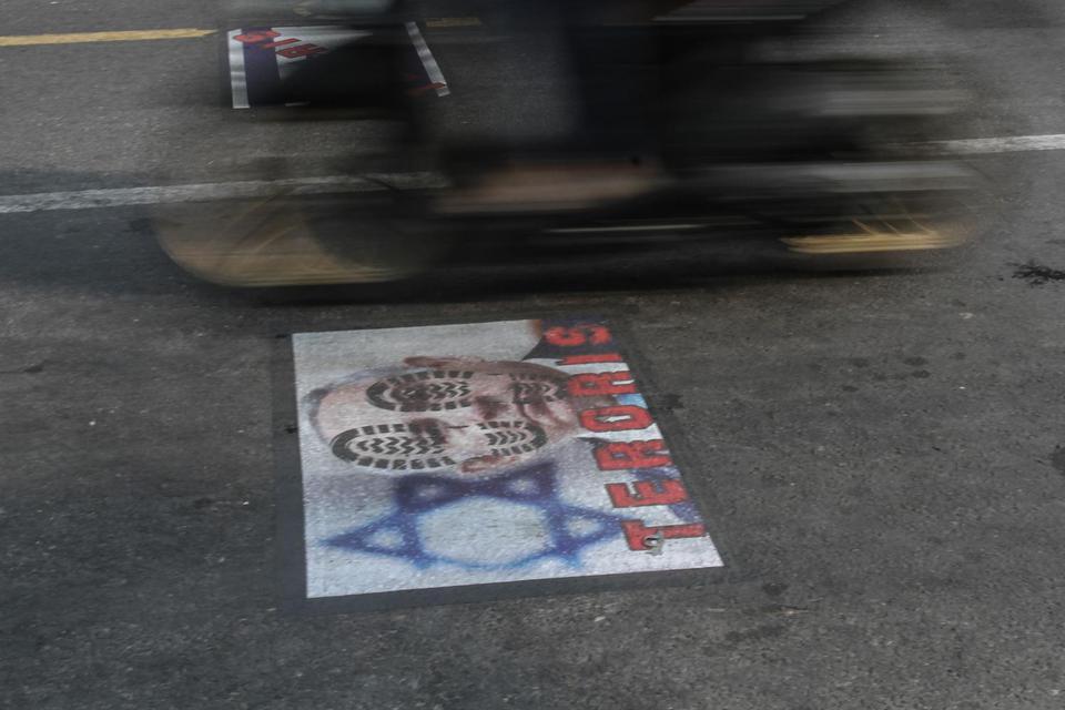 Warga melintasi poster bergambar PM Israel Benjamin Netanyahu yang ditempel di Jalan Jogokariyan, Yogyakarta, Minggu (23/5/2021). 