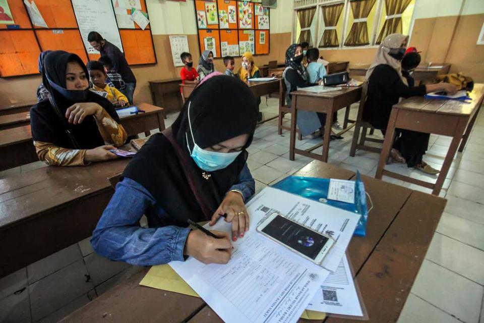 Orang tua calon siswa mengisi formulir pendaftaran siswa baru di Sekolah Dasar Negeri 1(SDN) Lhokseumawe, Aceh, Senin (24/5/2021). Pemerintah setempat membuka pendaftar siswa baru jenjang SD,SMP, SMA, SMK, dan SLB dan Pembelajaran secara tatap muka terbat