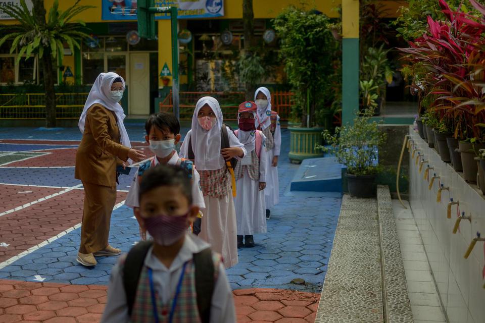 Sejumlah siswa menjaga jarak untuk keluar sekolah saat simulasi pembelajaran tatap muka di SD Cimahi Mandiri 2, Cimahi, Jawa Barat, Senin (24/5/2021). Pemerintah Kota Cimahi menggelar simulasi pembelajaran tatap muka di 27 PAUD/TK, 102 SD dan 38 SMP sebag