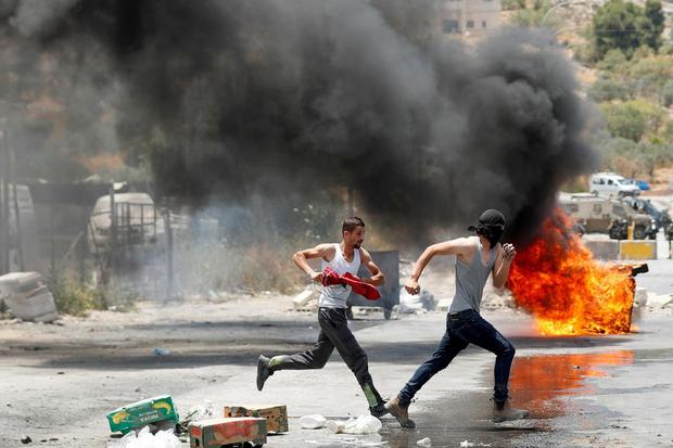 Mohamad Torokman Pengunjuk rasa Palestina berlari melewati barikade yang terbakar saat bentrok dengan pasukan Israel dalam sebuah protes terhadap perumahan Israel, di dekat Nablus di Tepi Barat, Selasa (8/6/2021). Agresi adalah fenomena yang dapat terjad