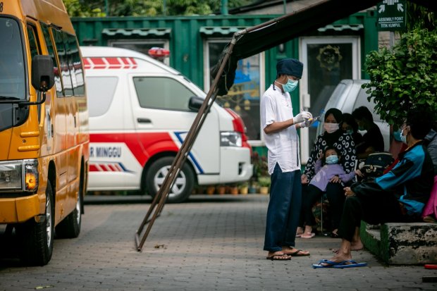 Petugas medis melakukan pendataan terhadap masyarakat yang terkonfirmasi positif Covid-19 sebelum diberangkatkan menggunakan bus sekolah untuk dirujuk ke sejumlah lokasi penanganan Covid-19 di Puskesmas Kecamatan Pasar Minggu, Jakarta, Sabtu, (12/6/2021).