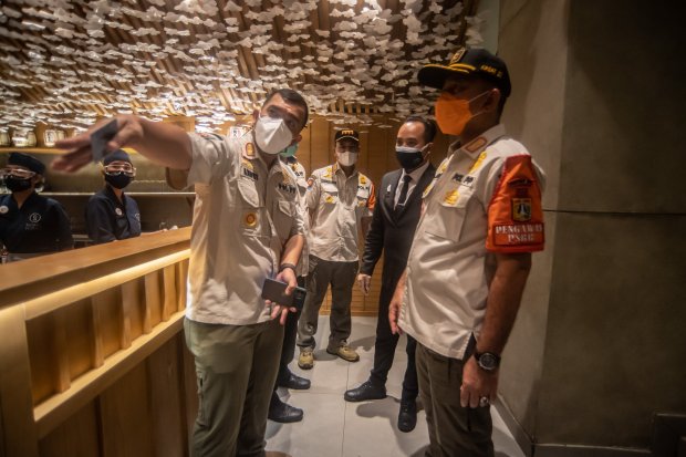 Petugas Satpol PP melakukan pemeriksaan terkait pelanggaran protokol kesehatan COVID-19 di rumah makan Sushi Hiro, Jakarta, Minggu (13/6/2021). Epidemiolog mengingatkan ancaman kenaikan kasus Covid-19 jika kebijakan Pemberlakuan Pembatasan Kegiatan Masyar