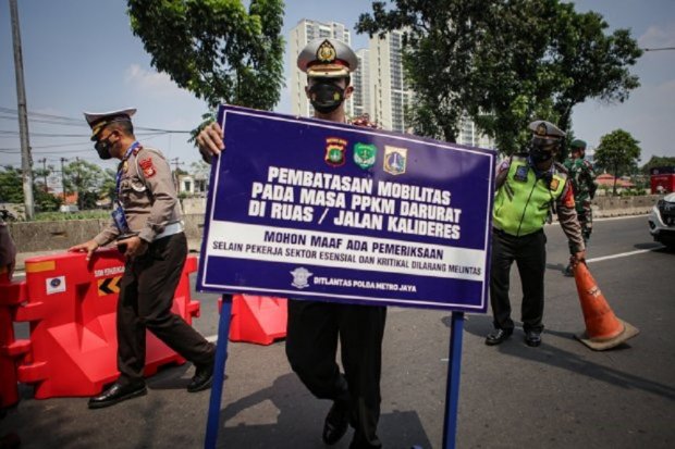 Petugas kepolisian mengangkat papan informasi pembatasan mobilitas PPKM Darurat di pos penyekatan pembatasan menuju Jakarta di kawasan Kalideres, Jakarta, Minggu (4/7/2021). Polisi mulai Kamis (14/7) menambah titik penyekatan saat PPKM darurat di Jadetabe