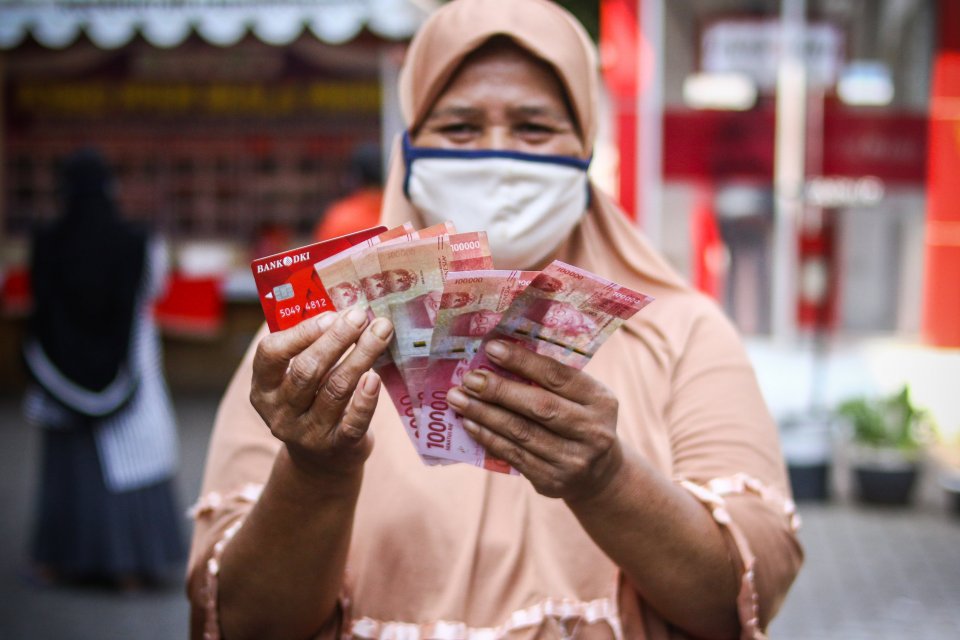 Warga menunjukkan uang bantuan sosial tunai atau BST usai mengambil di ATM Bank DKI, Jakarta, Selasa (20/7/2021). Pemprov DKI menyiapkan anggaran Rp604 miliar untuk bantuan sosial tunai atau BST kepada 1 juta Kepala Keluarga (KK) penerima manfaat selama P