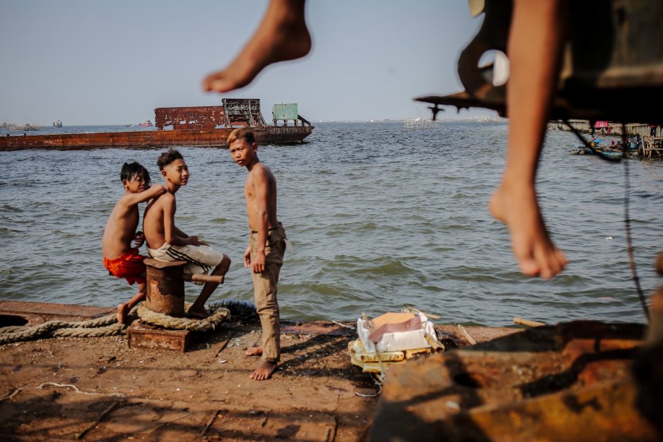 Sejumlah bocah bermain di atas kapal karam yang berada dekat tanggul raksasa (Giant Sea Wall) di wilayah pesisir Cilincing, Jakarta Utara, Selasa, (3/8/2021). Presiden Amerika Serikat (AS) Joe Biden belum lama menyatakan prediksi tenggelamnya DKI Jakarta