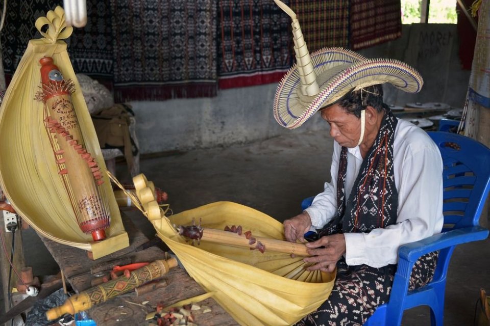 Ilustrasi seorang seniman tradisional asal Nusa Tenggara Timur yang sedangmempersiapkan alat musik tradisional Sasando