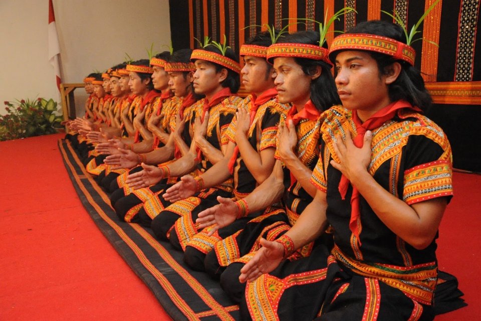 Pertunjukan Tari Saman dengan para penari yang duduk atau berlutut, bertepuk tangan, dada dan lutut, sambil menyanyikan syair mengikuti pemimpin (penangkat).