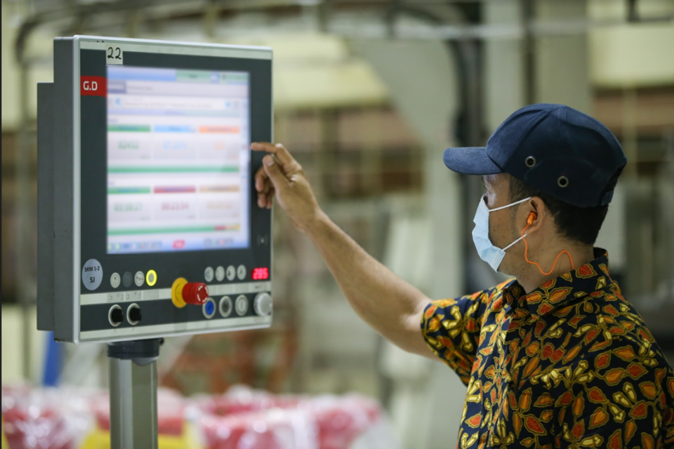 Karyawan Sampoerna sedang memeriksa operasional fasilitas produksi melalui mesin yang terdigitalisasi. 