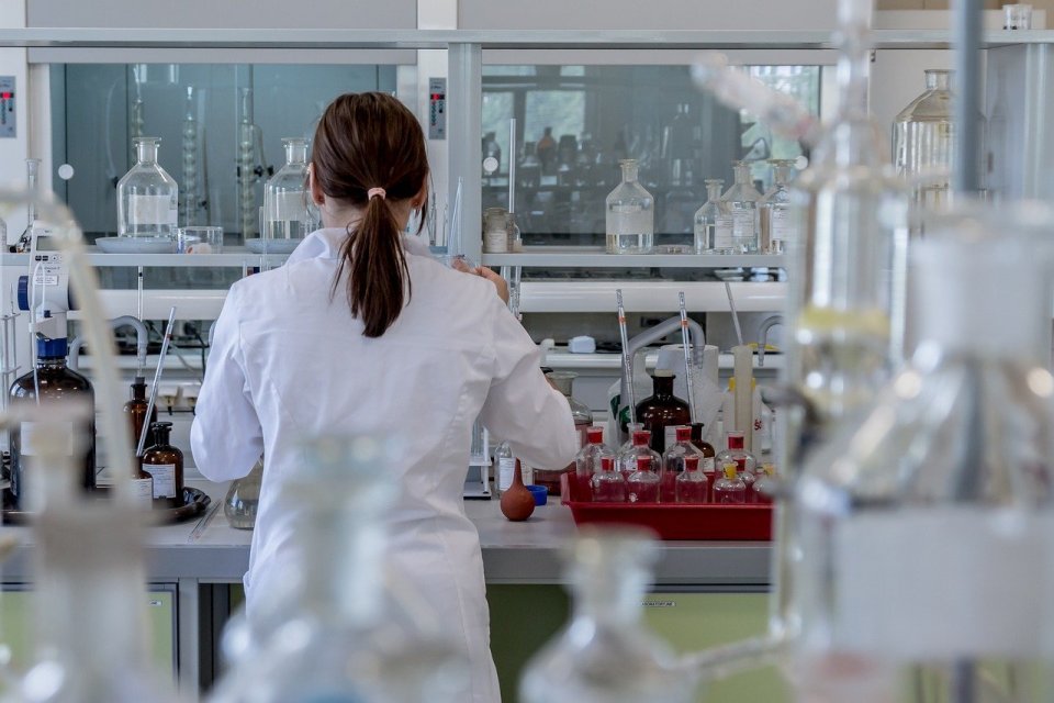 Ilustrasi seorang perempuan sedang melaksanakan eksperimen di laboratorium dengan menerapkan metode ilmiah biologi 