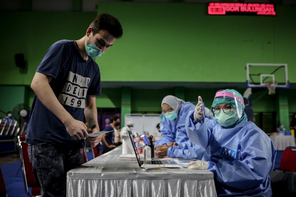 Petugas medis mengarahkan pencari suaka saat vaksinasi COVID-19 di GOR Bulungan, Jakarta Selatan, Kamis (7/10/2021). Vaksinasi tersebut digelar atas kerja sama Pemprov DKI Jakarta, UNHCR dan Kadin Indonesia. Sebanyak 600 vaksin dosis pertama disediakan da