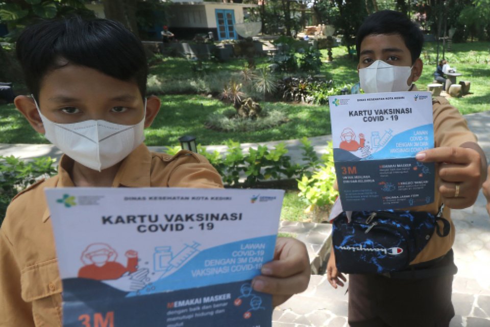 Siswa SD memperlihatkan kartu vaksinasi usai mendapatkan suntikan vaksin COVID-19 di Taman Hutan Kota Joyoboyo, Kota Kediri, Jawa Timur, Jumat (22/10/2021). Pemerintah daerah setempat berupaya mempercepat vaksinasi COVID-19 melalui vaksinasi massal kepada