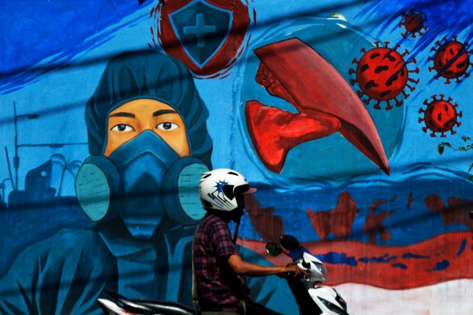 Pengendara melintas di depan mural bertema COVID-19 di kawasan Jalan Nusantara, Makassar, Sulawesi Selatan, Senin (1/11/2021)