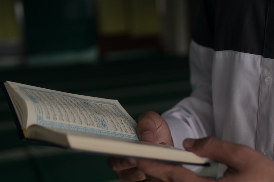Ilustrasi seorang membaca surat Al Maun dalam Al-Quran 