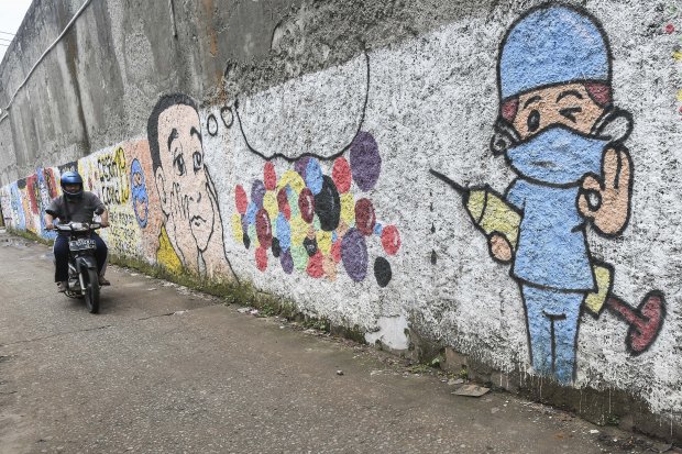 Pengendara motor melintasi mural bertemakan sosialisasi untuk vaksinasi COVID-19 di Bekasi, Jawa Barat, Senin (15/11/2021).