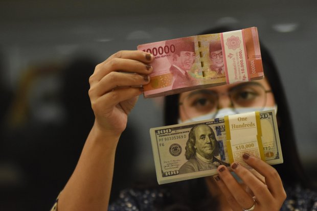 Pegawai menunjukkan mata uang rupiah dan dolar AS di salah satu gerai penukaran mata uang di Jakarta, Jumat (5/11/2021). 