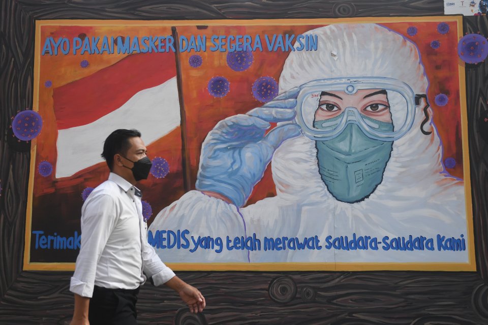 Warga melintas di dekat mural bertema COVID-19 di Jakarta, Rabu (1/12/2021).