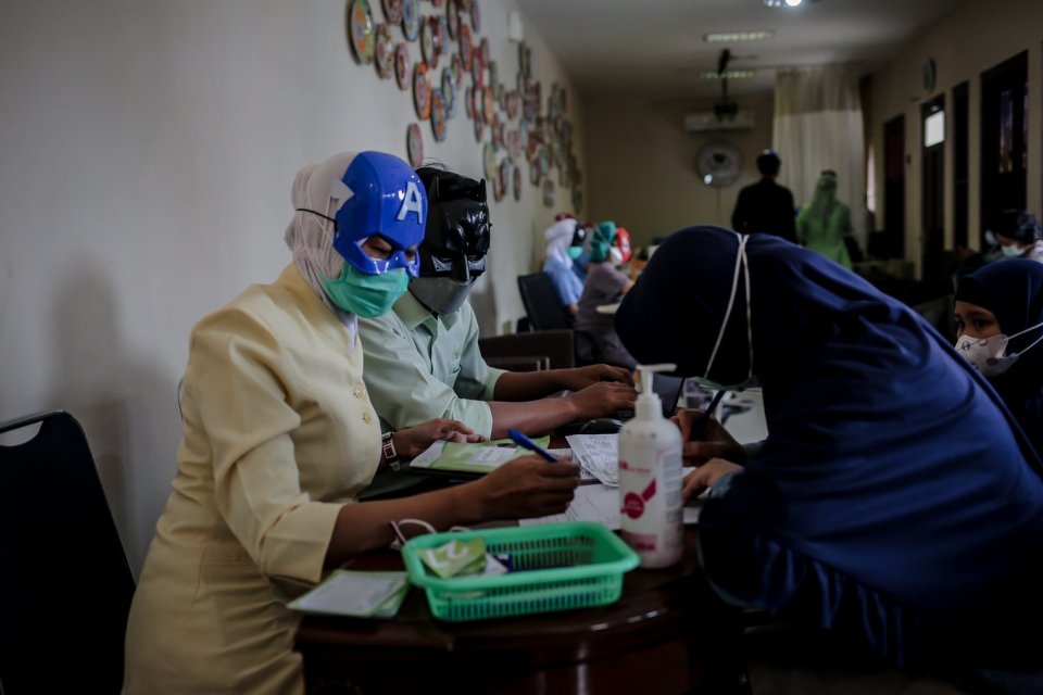 Petugas Kesehatan menegakan topeng super hero melakukan registrasi sebelum menyuntikkan vaksin covid-19 untuk anak-anak usia 6-11 tahun di Rumah Sakit Ibu dan Anak (RSIA) Tambak, Jakarta, Rabu (22/12/2021). Upaya tersebut dilakukan pihak rumah sakit untuk