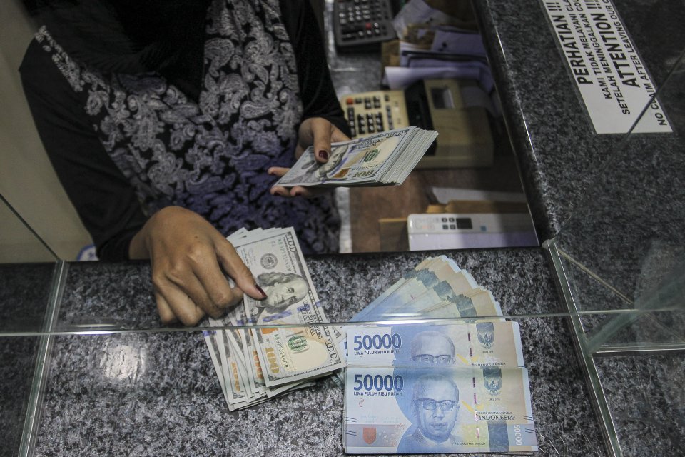 Pekerja menghitung uang dolar AS dan Rupiah di salah satu gerai penukaran mata uang di Jakarta, Rabu (5/1/2022).