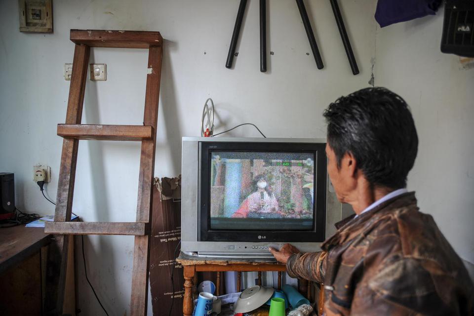 Seorang petugas keamanan menonton siaran TV analog di Cinunuk, Kabupaten Bandung, Jawa Barat, Kamis (17/2/2022). 