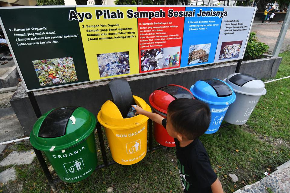 Seorang anak membuang sampah pada tempat sampah yang disediakan di Lapangan Vatulemo di Palu, Sulawesi Tengah, Selasa (22/2/2022). Pemerintah mengajak masyarakat untuk mulai memilah sampah guna mengurangi timbulan sampah pada tempat pembuangan akhir (TPA)