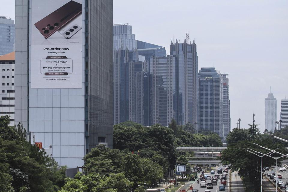 Sebuah reklame terpasang di antara gedung bertingkat di Jakarta, Rabu (23/2/2022). Kementerian Keuangan mencatat realisasi sementara APBN 2022 pada Januari 2022 mengalami surplus Rp28,9 triliun yang ditopang oleh melesatnya penerimaan pajak sebesar 59,39 