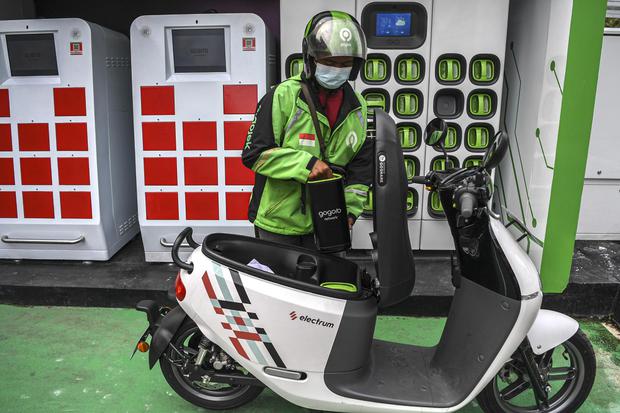 Seorang pengemudi ojek daring mengganti baterai sepeda motor listrik dengan yang sudah penuh terisi di Stasiun Penukaran Baterai Kendaraan Listrik Umum (SPBKLU) di SPBU Pertamina, Jalan MT Haryono, Jakarta, Jumat (4/3/2022). Pemerintah Indonesia menargetk