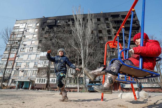 Alexander Ermochenko Sejumlah anak bermain di depan gedung yang rusak ditengah konflik Rusia-Ukraina, di kota pelabuhan yang terkepung Mariupol, Ukraina, Rabu (23/3/2022).