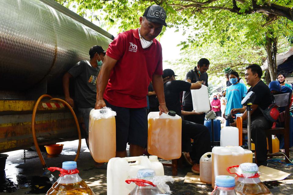 Pedagang mengangkut jeriken berisi minyak goreng curah yang dibeli saat digelar operasi pasar di Pasar Dungus, Kabupaten Madiun, Jawa Timur, Kamis (24/3/2022).