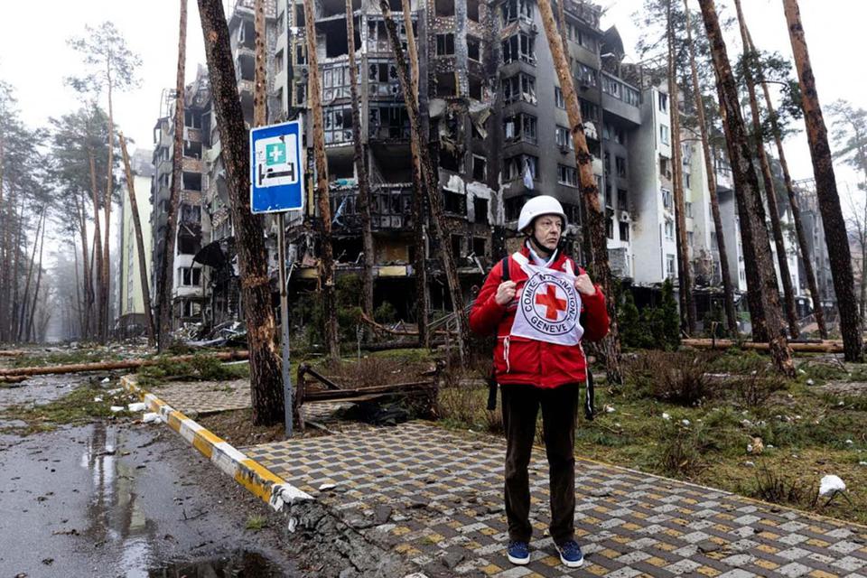 Anggota staf Palang Merah berdiri di dekat gedung yang rusak saat mengirimkan makanan dan pertolongan pertama kepada penduduk yang terkena dampak pertempuran selama invasi Rusia ke Ukraina, di Irpin, Jumat (1/4/2022).