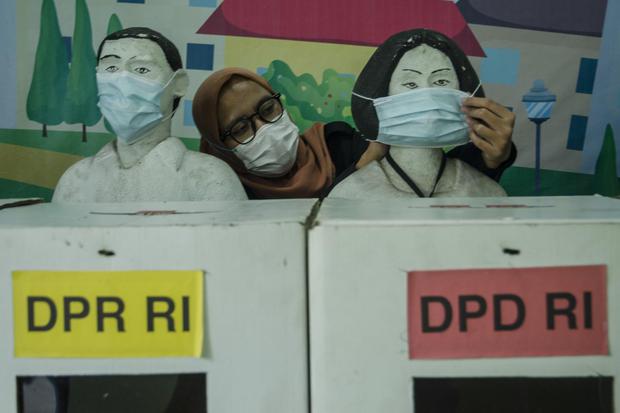Petugas merapikan masker yang dipasang pada diorama suasana pemungutan suara di TPS saat Pemilu di Kantor KPU Jawa Barat, Bandung, Jawa Barat, Kamis (7/4/2022). 