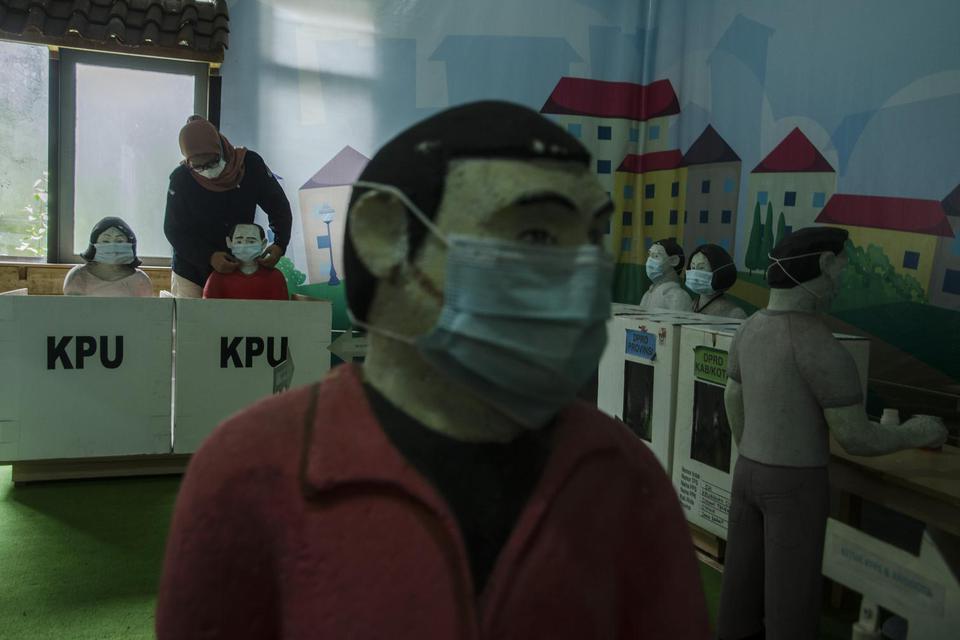 Petugas merapikan masker yang dipasang pada diorama suasana pemungutan suara di TPS saat Pemilu di Kantor KPU Jawa Barat, Bandung, Jawa Barat, Kamis (7/4/2022). 