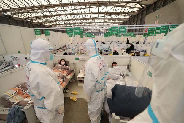 Petugas medis dengan alat pelindung diri berkeliling bangsal di Ruang Pameran Shanghai New International, yang diubah menjadi rumah sakit sementara untuk pasien penyakit virus korona (COVID-19), di Shanghai, China, Sabtu (9/4/2022). Foto diambil tanggal 9