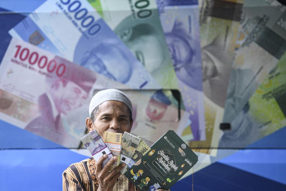 Warga menunjukkan uang baru yang ditukarkan pada mobil kas keliling Bank Indonesia (BI) di Pasar Koja Baru, Jakarta Utara, Rabu (13/4/2022). 