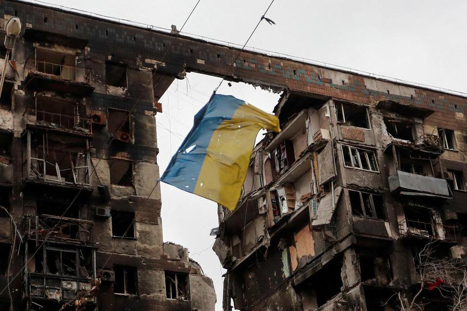 Alexander Ermochenko Sebuah pemandangan menunjukkan bendera Ukraina yang robek tergantung di kawat di depan sebuah gedung apartemen yang hancur selama konflik Ukraina-Rusia di kota pelabuhan selatan Mariupol, Ukraina, Kamis (14/4/2022).