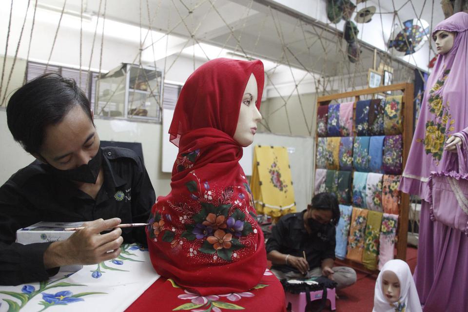 Karyawan menyelesaikan pembuatan jilbab lukis produksi Nasrafa di Sentra IKM (Industri Kecil Menengah) Semanggi Harmoni Solo, Jawa Tengah, Jumat (15/4/2022).